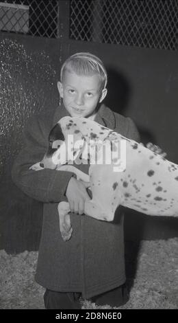 1948, historisch, ein kleiner Junge mit seinem neuen 'Freund', ein gefleckter Rettungshund bei einem Hundeheim, New York City, USA. Stockfoto