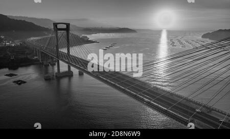 Luftaufnahme der Rande-Brücke bei Sonnenuntergang in schwarz-weiß. Puente de Rande, Rande, Vigo, Pontevedra, Galicien, Spanien Stockfoto