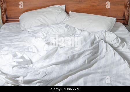 Ungemachtes Bett mit weißer Bettwäsche. Ungemachtes leeres Bett. Nahaufnahme von ungemachten Bettlaken im Schlafzimmer nach dem Schlafen Stockfoto