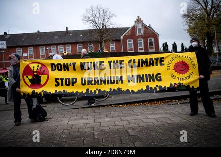 31. Oktober 2020, Niedersachsen, Nordenham: Demonstranten halten ein Protestplakat mit der Aufschrift "Klima nicht nucken, Uranabbau stoppen" (zum Beispiel: Klima nicht nucken, Uranabbau stoppen). Sechs Castor-Container mit hochradioaktivem Kernabfall aus der britischen Wiederaufbereitungsanlage Sellafield sind auf einem Spezialschiff auf dem Weg nach Deutschland. Die Ladung soll auf der Schiene zum Zwischenlager in Biblis, Hessen, transportiert werden. Atomgegner und Umweltschützer gehen davon aus, dass die Container im niedersächsischen Hafen Nordenham von Schiff zu Schiene transportiert werden. Stockfoto