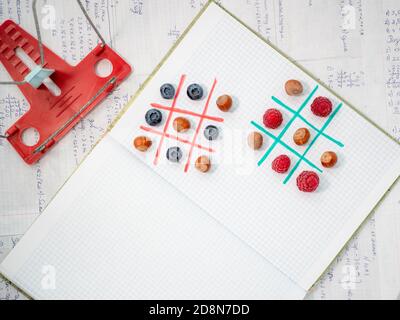 Fröhliches Lernen ohne Langeweile beim Spielen schmackhafter Spiele. Mittagspause mit Schulfreunden. Leerzeichen für Text. Lernen Sie mit Spaß. TIC-tac-Toe mit Beere. Stockfoto