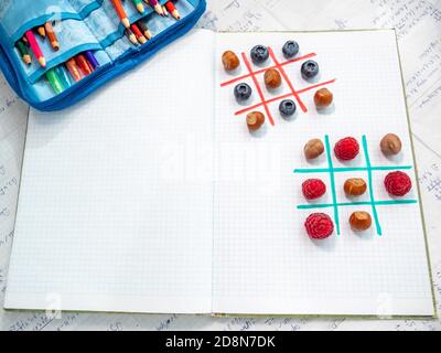 TIC tac toe wtih Beeren und Haselnüsse auf einer Mittagspause in der Schule. Studieren Sie mit Geschmack und Freude. Mittagspause mit Schulfreunden. Leerzeichen für Text. Stockfoto