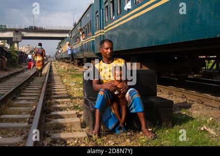 Dhaka, Dhaka, Bangladesch. Oktober 2020. Ein Eisenbahn-Slummann fand auf einem Sofa sitzen und hielt sein Kind, während ein Zug neben ihm lief. 31. Oktober 2020. Dhaka, Bangladesch. Kredit: Nayem Shaan/ZUMA Wire/Alamy Live Nachrichten Stockfoto