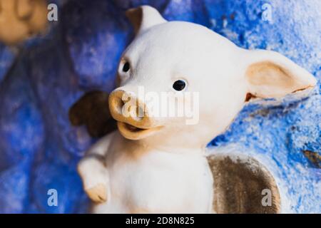 Geflügeltes Schwein aus Lehm und bemalt auf einer blauen Himmel Hintergrundwand. Stockfoto