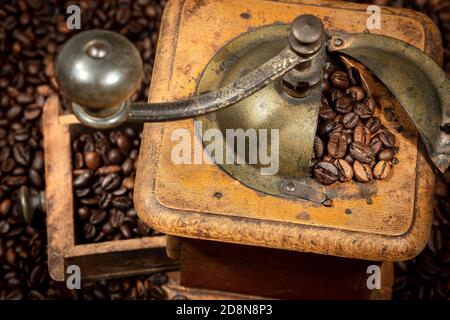 Nahaufnahme einer alten manuellen Kaffeemühle aus Metall und Holz mit gerösteten Kaffeebohnen, Venetien, Italien, Europa. Stockfoto