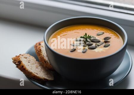 Kürbis- und Karottencremesuppe mit Kürbiskernen und geröstet Brot Stockfoto