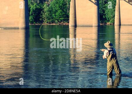 Person, Mann, watend in den Fluss unter einer Brücke, um Fische zu fliegen. Stockfoto