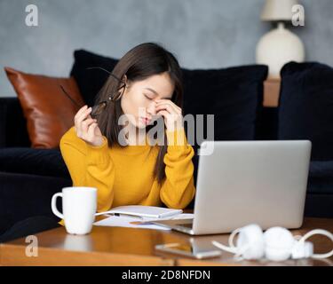 Asiatische Frau zu Hause arbeiten, schreiben Notebook. Schöne japanische Freiberuflerin Stockfoto