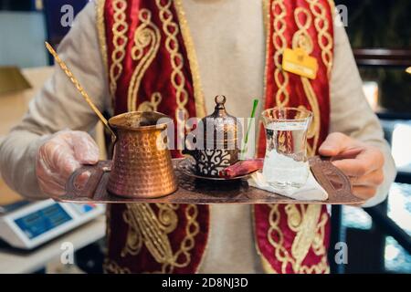 Ein Mann serviert ein Tablett mit traditionellen türkischen Kaffee auf dem Sand in Turku, selektive Fokus. Stockfoto