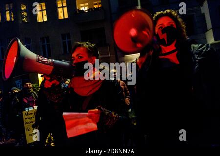 Berlin, Berlin, Deutschland. Oktober 2020. Bei einer Kundgebung unter dem Motto 'Wir sind richtig angePISsst!!' sind Demonstranten mit Megaphonen im roten Licht neben der St. Johannes-Basilika im Berliner Bezirk Kreuzberg zu sehen. Nachdem das polnische Verfassungsgericht, das von der nationalpopulistischen Regierungspartei PiS kontrolliert wird, das aktuelle Abtreibungsgesetz am 22. Oktober 2020 für verfassungswidrig erklärt hat und ein fast vollständiges Abtreibungsverbot ausgesprochen hat. Die Organisatoren fordern die Rücknahme der Entscheidung des Verfassungsgerichts, legale Abtreibung auf Antrag und volle reproducti Stockfoto