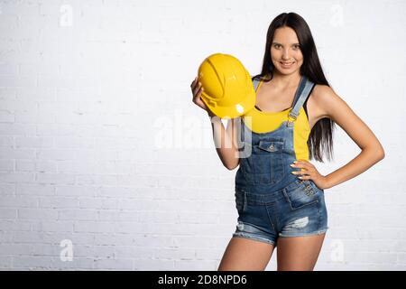 Ein freudiger Ansatz für die Arbeit auf einer Baustelle. Junge Bauarbeiterin. Mit einem Lächeln erinnert er Sie daran, dass ein Bauhelm ein wichtiges Sicherheitselement ist. Stockfoto