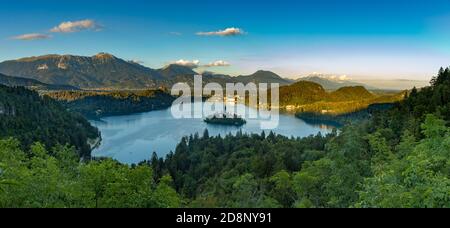 Ein Panoramabild des Bleder Sees und der umliegenden Landschaft, mit der Insel Bled in der Mitte, von einem Aussichtspunkt aus gesehen. Stockfoto
