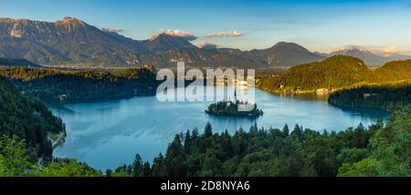Ein Panoramabild des Bleder Sees und der umliegenden Landschaft, mit der Insel Bled in der Mitte, von einem Aussichtspunkt aus gesehen. Stockfoto