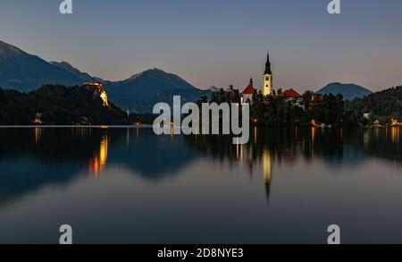 Ein Bild des Bleder Sees mit der Insel Bled und dem Schloss Bled am Abend. Stockfoto