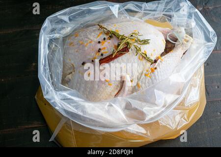 Einen truthahn in einer Plastiktüte bringen: Einen rohen truthahn in Bourbon-Sole mit Rosmarin, Zimtstangen, schwarzen Pfefferkörnern und Orangenschale Stockfoto