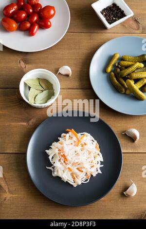 Verschiedene Arten Vorspeisen flach lag auf Holzhintergrund. Teller mit Sauerkrautkohl und eingelegten Gurken und Tomaten. Fermentiert und mariniert f Stockfoto