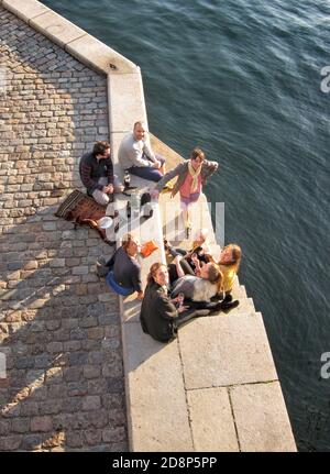 Junge Leute genießen Wein bei Sonnenuntergang auf dem Kanal in Kopenhagen, Dänemark. Stockfoto