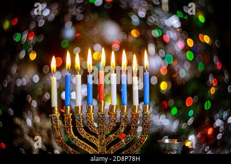 Brennende Kerzen mit Menorah für Hanukkah auf Unschärfe Farbe Lichter Hintergrund. Jüdischer Feiertag Stockfoto