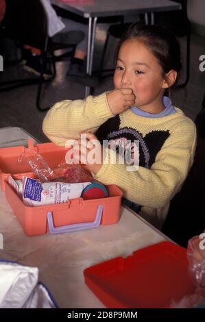 anglo-asiatische Mädchen mit Lunchpaket in der Grundschule Esszimmer Stockfoto