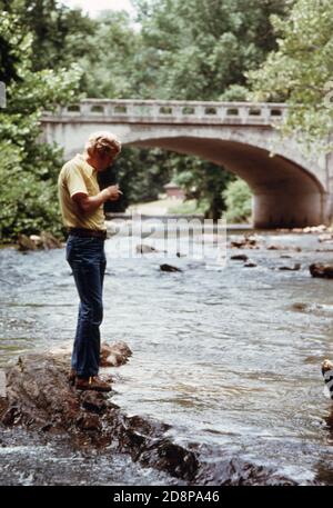 Tourist pausiert für einen Moment der Einsamkeit der Chattahoochee Fluss südlich der Georgia Highway 17/75 Brücke am westlichen Eingang zu Helen; eine kleine Berggemeinde von etwa 270 Menschen. Es war ein typisches Dorf in der Gegend bis 1969, als lokale Beamte Geschäftsleute und Bewohner befürworteten die Renovierung des Geschäftsviertels mit einem bayerischen alpinen Thema. Der Erfolg des Projekts zog neue Unternehmen und einen Anstieg der Touristen zwischen Mai und Oktober. Stockfoto