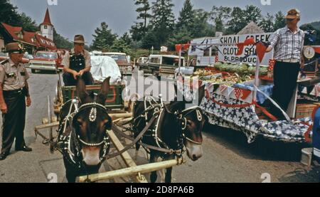 Polizist von Helen; Georgien; chattet mit Teilnehmern der Parade vom 4. Juli, während sie die Hauptstraße entlang fahren. Helen war ein typisches kleines Bergdorf mit weniger als 300 Einwohnern bis Anfang 1969, als Stadtbeamte, Geschäftsleute und Bewohner die Renovierung des Geschäftsviertels mit einem bayerischen alpinen Thema befürworteten.das Projekt war ein Erfolg und zog neue Geschäfte und eine Welle von Touristen an. Ein Planungsbericht weist darauf hin, dass ein Gleichgewicht zwischen Wachstum und öffentlichem Interesse erforderlich ist. Stockfoto