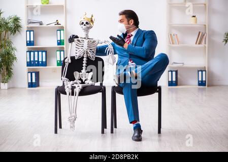 Geschäftsmann und Skelett im Büro in Pandemiekonzept Stockfoto