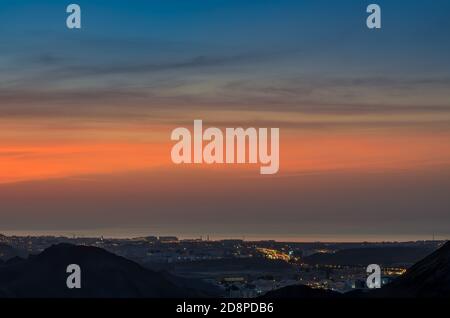 Schöner blauer & oranger Himmel über Muscat, Oman in der Nacht Stockfoto