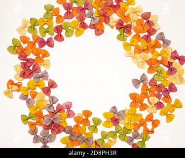 Foto italienische RAW mehrfarbige Farfalle Pasta auf weißem Hintergrund mit Kopierraum. Bunte Pasta in Form einer Fliege. Das Konzept des Italienischen Stockfoto