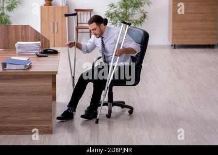 Am Arbeitsplatz erkrankt ein junger, am Bein verletzter Mitarbeiter Stockfoto