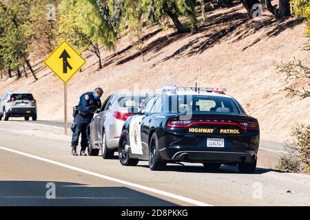 Oct 14, 2020 Fremont / CA / USA - Highway Patrol Officer schreibt ein Verkehrsticket an einen Fahrer, der auf der rechten Straßenseite herüberfährt Stockfoto