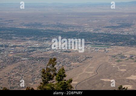 Blick von den Sandia Mountains nach North Albuquerque und den Rio Grande River, der einen grünen Weg durch die Wüstenlandschaft schneidet. Stockfoto