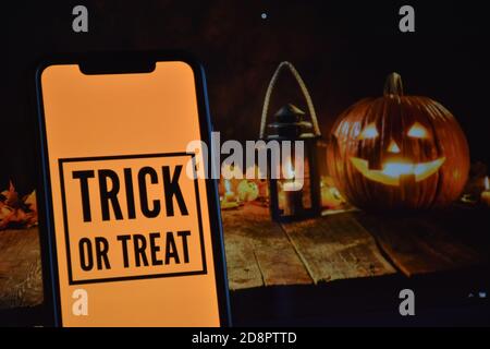 Trick or Treat Text auf Handy mit Halloween-Hintergrund Stockfoto