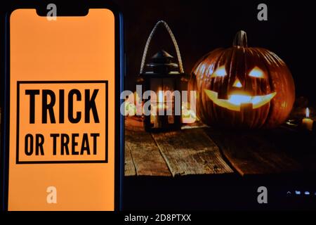 Trick or Treat Text auf Handy mit Halloween-Hintergrund Stockfoto