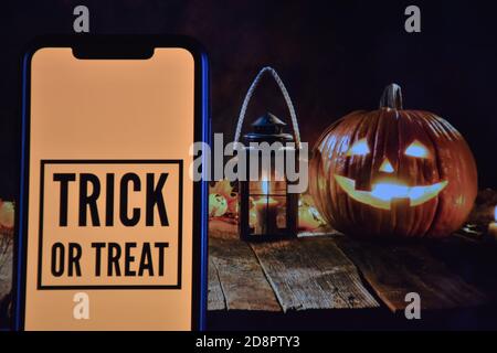 Trick or Treat Text auf Handy mit Halloween-Hintergrund Stockfoto