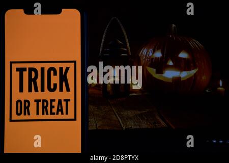 Trick or Treat Text auf Handy mit Halloween-Hintergrund Stockfoto