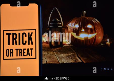 Trick or Treat Text auf Handy mit Halloween-Hintergrund Stockfoto