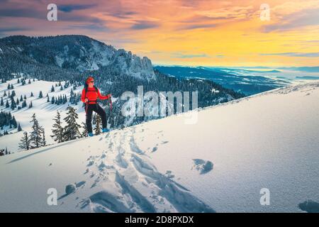 Fröhliche sportliche Frau auf frischem Pulverschnee, Skitouren auf den verschneiten Hügeln. Backcountry Skifahrerin Frau mit Rucksack genießen die Aussicht bei Sonnenuntergang, Carpath Stockfoto