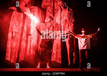 Krakau, Polen. Oktober 2020. (ANMERKUNG DER REDAKTION: Bild enthält Obszönität) EIN Protestler mit einem roten Fackel steht auf einem Denkmal während der Demonstration.das polnische Verfassungsgericht in seiner neuen, Politisch gewähltes Gerichtsgebäude entschied, dass Abtreibung verfassungswidrig ist in Fällen, in denen es eine hohe Wahrscheinlichkeit von schweren und irreversiblen Schäden am Fötus oder eine unheilbare Krankheit, die sein Leben bedroht. Im Falle Polens bedeutet dies fast ein totales Abtreibungsverbot. Als Folge der Entscheidung des Gerichts begannen große Proteste in jeder größeren Stadt in Polen. Fast eine Woche lang blockieren die Polen Stockfoto