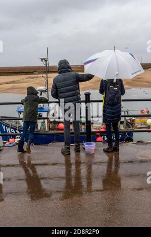 Eine Familie, die auf einem Pier am Meer auf einem Urlaub in großbritannien oder einem Aufenthalt in Großbritannien steht Stockfoto