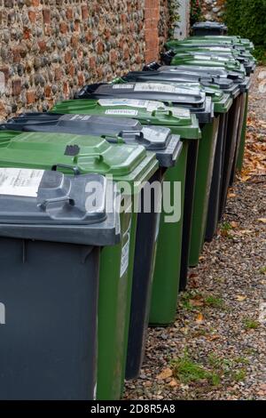 Eine Reihe von grünen und schwarzen Kunststoff-Recycling-Behältern oder Mülltonnen für die Abfallentsorgung. Stockfoto