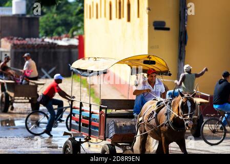 Lächelnder Mann, der während der morgendlichen Hauptverkehrszeit auf einer Trinidad-Straße einen Wagen fährt. Kubanische Straßenszene. Stockfoto