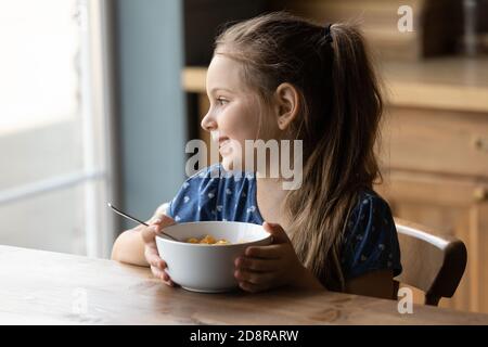 Lächelndes kleines Mädchen essen gesundes Frühstück zu Hause Stockfoto