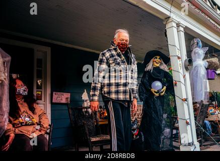 Zwei Hausbesitzer sitzen auf ihrer festlichen, geschmückten Veranda, während sie warten, um Süßigkeiten an Trick-or-treaters während Oakwoods erstem "COVID-19 Halloween" zu übergeben. Normalerweise erwartet Volusia Hunderte von Trick-or-Treatern, aber während des ersten "COVID-19 Halloween" in Amerika spielten Eltern es sicher, Familien trugen Masken mit ihren Kostümen und Eltern sorgten dafür, dass ihre Kinder ihre Masken nicht auszogen oder zu nahe an diejenigen kamen, die sie nicht kannten, aufgrund von Coronavirus-Ängsten. Viele entschieden sich ganz aus den Festlichkeiten, aber diejenigen, die aus wagten, wurden mit Eimern voller Süßigkeiten und gutherzig, aber DIS erfüllt Stockfoto