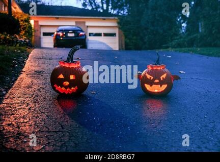 Zwei Jack-o-Laternen leuchten auf einer Auffahrt, als die Sonne während Oakwoods erstem 'COVID-19 Halloween' untergeht. Normalerweise erwartet Volusia Hunderte von Trick-or-Treatern, aber während des ersten "COVID-19 Halloween" in Amerika spielten Eltern es sicher, Familien trugen Masken mit ihren Kostümen und Eltern sorgten dafür, dass ihre Kinder ihre Masken nicht auszogen oder zu nahe an diejenigen kamen, die sie nicht kannten, aufgrund von Coronavirus-Ängsten. Viele entschieden sich ganz aus den Festlichkeiten, aber diejenigen, die aus wagten, wurden mit Eimern voller Süßigkeiten und gutherzige, aber distanzierte Wellen von Nachbarn erfüllt. Stockfoto