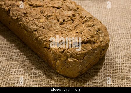 Frisches hausgemachtes Brot - Bio hausgemachtes Vollkornbrot. Frisches selbstgebackenes Brot. Das Brot ist auf einem Jute-Material. Nahaufnahme - Backkonzept.. Stockfoto