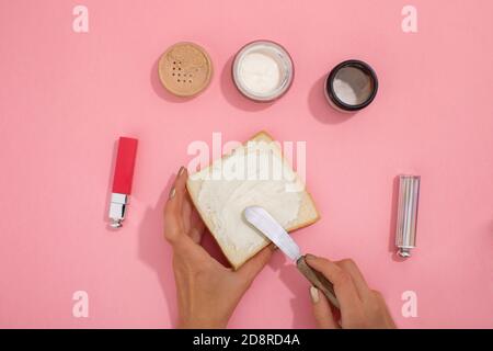 Hände schmieren kosmetische Creme auf Brot Stockfoto