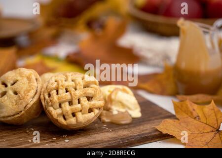 Herbst Mini Apfelkuchen mit Gitter, Eis, Karamellsauce und Blättern Stockfoto