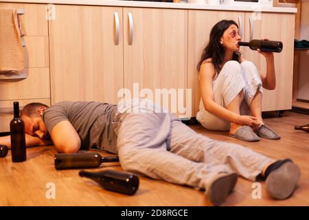 Opfer von häuslicher Gewalt Alkohol trinken und betrunkenen Mann schlafen auf Küchenboden nach der Frau zu schlagen. Aggressiver Ehemann missbraucht Verletzungen erschrocken, Angst, geschlagen und in Panik Wman . Stockfoto