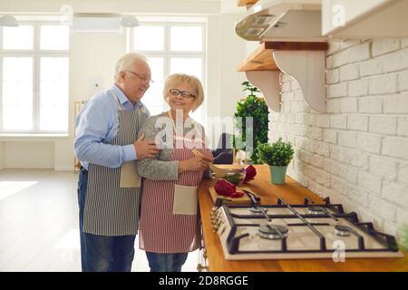 Glückliches Senior-Paar, das gesundes vegetarisches Essen kocht und auf der Arbeitsfläche steht In der Küche Stockfoto