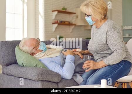 Ältere Frau hilft kranken Mann Medizin zu nehmen und zu fragen Wenn er etwas braucht Stockfoto
